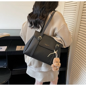 Détail du sac cabas en cuir grainé noir avec boucle dorée et breloque ours marron