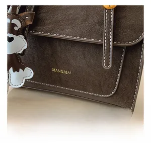 Detail of dark brown vintage faux leather backpack with white stitching and dog charm