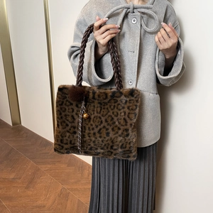Detail of leopard print faux fur tote with woven handles and fluffy pom pom charm