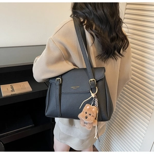 Détails du cabas en cuir grainé noir avec boucles dorées et charm chien en peluche