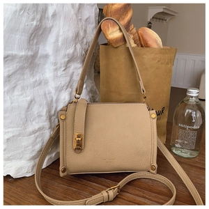 Detailed close-up of apricot lychee pattern leather bag with golden metal lock detail