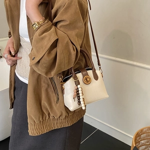 Retro cremefarbene Muscheltasche mit braunem Griff und Quaste, getragen zum Wildleder