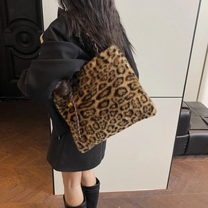 Detail of leopard print plush tote bag featuring woven straps and bell tassel charm