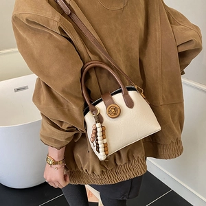 Nahaufnahme der Muscheltasche mit genarbtem Leder und dekorativem Perlenanhänger