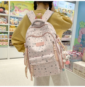 Detalle de mochila rosa floral con patrones de estrellas y colgante de oso de peluche suave