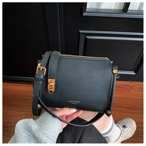 Detail of lychee pattern leather texture with gold zipper and metal buckle on black crossbody bag