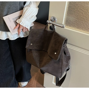 Close-up of a matte dark brown retro backpack with double silver buckles and flap design