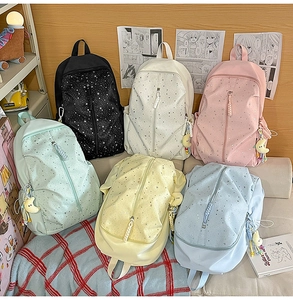 Detail view of colorful school backpacks with star patterns and plush moon pendants