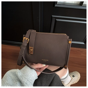 Detail of dark brown pebble leather bag with gold hardware and logo print