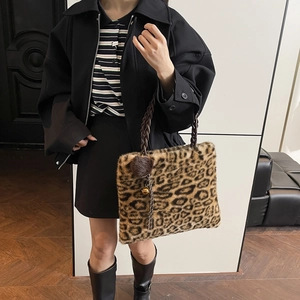 Detail of plush leopard print tote bag with woven brown handle and decorative gold bell charm
