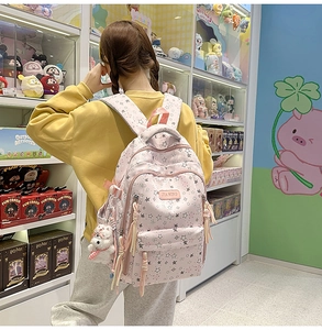 Detalle de mochila rosa con bolsillos con cremallera y un colgante de oso de peluche blanco