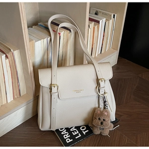 Détail du sac cabas en cuir beige avec boucles dorées et pendentif chiot en peluche doux