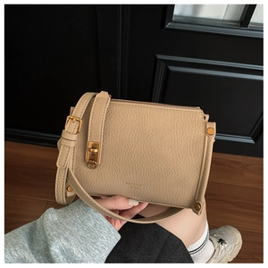 Detailed macro view of litchi textured leather handbag with premium golden hardware