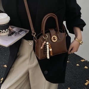 Detail der braunen Vintage-Lederhandtasche mit Rundverschluss und Perlenanhänger
