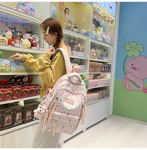 Detalle de mochila rosa con patrones de estrellas, colgante de peluche y logo de marca en cuero