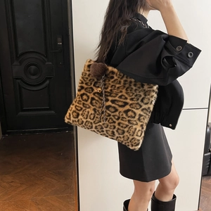 Detail of leopard print plush tote bag with brown pompom and bell charm accessories