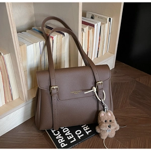 Détail du sac cabas en cuir grainé marron avec boucles dorées et breloque peluche