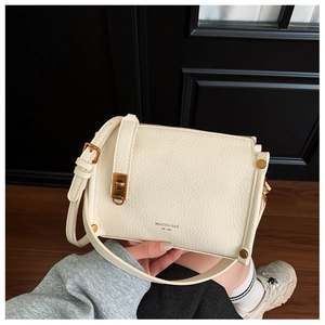 Detailed view of white lychee leather texture and vintage gold buckle on a square bag
