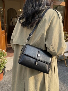 Minimalist black leather shoulder bag with vintage metal buckle and flap closure