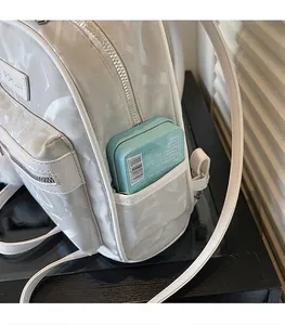 Detail of the side pocket on a white faux leather backpack with metallic logo