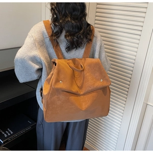 Caramel brown matte leather backpack with silver studs shown on a model's back