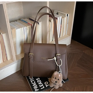 Détail d'un sac cabas en cuir grainé avec boucle dorée et breloque en forme d'ours