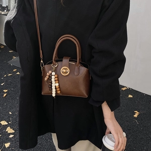 Details der braunen Vintage-Tasche mit goldenem Drehverschluss und farbigem Perlenanhänger