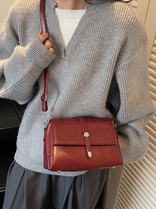 Retro burgundy leather crossbody bag with silver buckle worn by a model on shoulder
