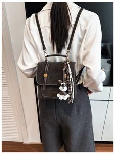 Detail of vintage gray backpack with white contrast stitching and cute dog charm