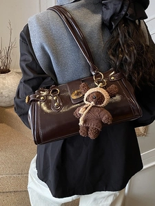 Vintage dark brown patent leather Boston bag with plush bear charm worn by a model