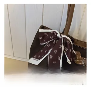 Close-up of brown suede tote bag featuring a teddy bear print silk scarf and silver buckle