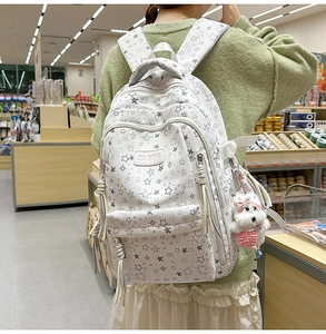 Detalle de mochila blanca con estrellas y un pequeño perro de peluche colgado