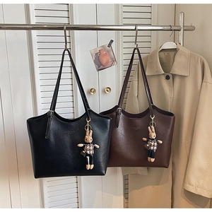 Detailed view of large tote bags in black and brown with cute rabbit charms on hangers