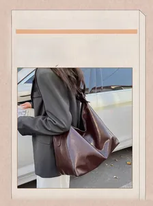 Vue de rue d'un grand sac cabas marron foncé brillant porté par un mannequin