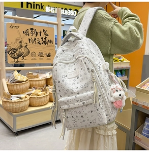 Detalle de la mochila blanca con estampado de estrellas y un lindo llavero de perro
