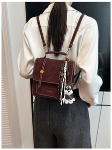 Detail of burgundy vintage backpack with white contrast stitching and puppy charm