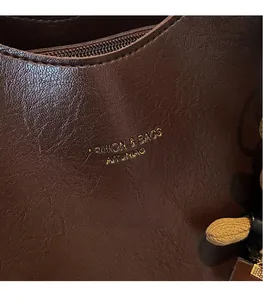 Close-up of deep brown leather texture with golden brand logo and smooth metal zipper
