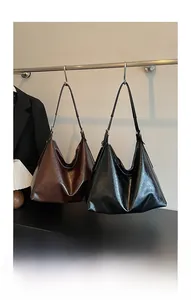Detail of vintage large hobo shoulder bags in brown and black glossy cracked leather