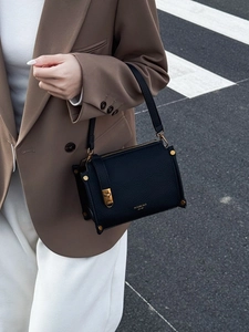 Classic black litchi texture square handbag with gold buckle and leather strap on street