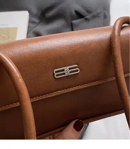 Detail of a brown leather shoulder bag featuring a polished silver-tone double B logo