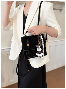 Detail showing the black vintage crossbody bag with a dog-shaped charm and gold buckle
