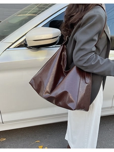 Grand sac à main marron porté à l'épaule dans une scène quotidienne de trajet
