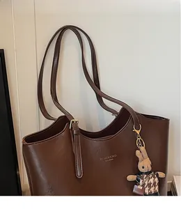 Detail of deep brown faux leather tote with golden logo and a rabbit charm pendant