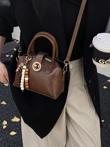 Retro dunkelbraune Muscheltasche mit Goldschließe und Perlenanhänger in Straßenszene