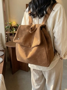 Retro caramel brown suede backpack featuring a large flap and metallic rivet accents