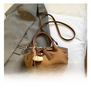Macro shot of brown pebble grain bucket bag with fringe and coffee bead pendant details