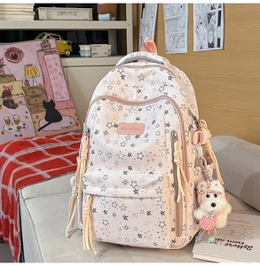 Detalle de mochila rosa con estrellas, colgante de perro blanco y cintas decorativas