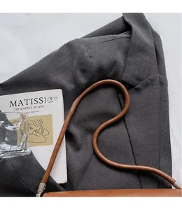 Detail of smooth leather shoulder strap with silver metal buckle on a brown baguette bag