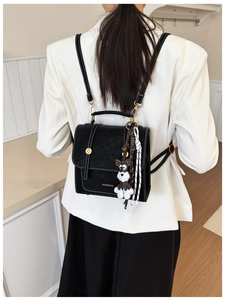 Detail of black PU backpack featuring white contrast stitching and gold magnetic clasp