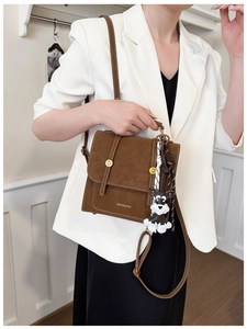 Detail of vintage dark brown crossbody bag with metal buckles and dog charm pendant